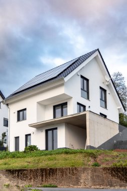 Banliyöde yeni evler inşa etmek. İnşaatın son aşamalarında çatıda güneş panelleri olan yeni bir bina.