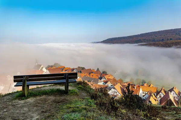 Empty bench on the top of the hill against the background of the city covered with fog, beautiful view near town of Schieder-Schwalenberg in the state of North Rhine-Westphalia in Germany