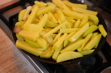 Tavada kızarmış patates. Kızartma tavasında taze patates ve ayçiçeği yağı. Kızartma tavasında patates kızartması. Kızarmış patatesle dolu tavalı fırın manzarası