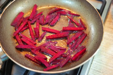 Kızartma tavasında pancar dilimleri. Büyük pancar parçaları tavada kızartılır. Sağlıklı yemek. Vejetaryen yemeği. Ev mutfağı. Kavrulmuş pancar dilimleri, tavada peynir, yakın plan.