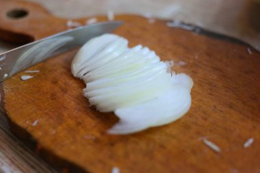 Soğan doğrama. Ahşap tahtanın soğanını bıçakla kesen şefin elleri. Yemek hazırlığı. Sağlıklı beslenme ve yaşam tarzı. Adam beyaz soğanı bıçakla kesiyor. Ev mutfağı. Yemek pişirme.