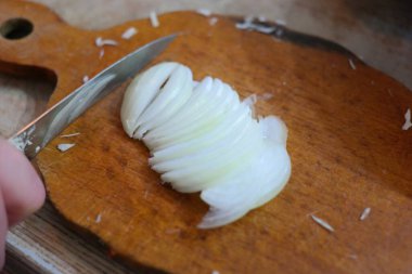 Soğan doğrama. Ahşap tahtanın soğanını bıçakla kesen şefin elleri. Yemek hazırlığı. Sağlıklı beslenme ve yaşam tarzı. Adam beyaz soğanı bıçakla kesiyor. Ev mutfağı. Yemek pişirme.