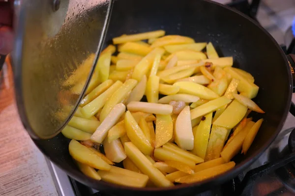 fried potatoes in a pan. Frying fresh potatoes in a frying pan with sunflower oil. Fried potatoes in a frying pan. View of cooker with frying pan filled with fried potatoes