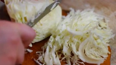 lahana öğütücü. Lahana turşusu pişirmek, bıçakla lahana ve havuç kesmek. Rendelenmiş lahana kompozisyonu. Yanında rendeleyici ve lahana var. Masada kesilmiş lahana olan tahta tahta tahta..