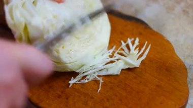 lahana öğütücü. Lahana turşusu pişirmek, bıçakla lahana ve havuç kesmek. Rendelenmiş lahana kompozisyonu. Yanında rendeleyici ve lahana var. Masada kesilmiş lahana olan tahta tahta tahta..