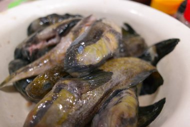 Balık temizliği. Gobiidae. Balık pişirmek. Kavanozda balık. Ev yemeği. Şef, beyaz çiğ balığı pazar için hazırlıyor. Fileto ve fileto, tüm morina balığını bıçakla keser. gobiformes