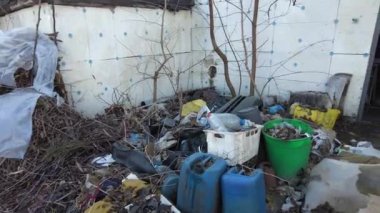 Ukrayna 'da terk edilmiş bir ev. Bahçedeki çöpler. Evi yıktı. İnşaat alanı. İnşaat atıkları. Çöp yığını. Yıkılmış ev. Felaketler binayı yok etti. Çevre kirliliği. 4k fo