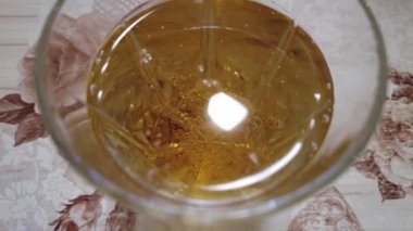 şeffaf bardakta limonata. 4K görüntü. Yakından bir bardağa karbonatlı içecek dolduruyorum. Kola köpüklü, buzlu, şeffaf bardaklı, mavi arka planda köpüklü içecek..