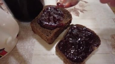 Ekmeğe reçel sür. Yüksek kalite 4K görüntü. Düşük kalorili orman meyveli reçeli ekmekli tost. Mutfakta fıstık ezmeli sandviç yapıyorum. Ekmeğe çilek reçeli sürüyorum..