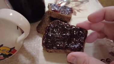 Ekmeğe reçel sür. Yüksek kalite 4K görüntü. Düşük kalorili orman meyveli reçeli ekmekli tost. Mutfakta fıstık ezmeli sandviç yapıyorum. Ekmeğe çilek reçeli sürüyorum..