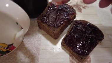 Ekmeğe reçel sür. Yüksek kalite 4K görüntü. Düşük kalorili orman meyveli reçeli ekmekli tost. Mutfakta fıstık ezmeli sandviç yapıyorum. Ekmeğe çilek reçeli sürüyorum..