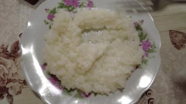Tabakta pirinç lapası. Haşlanmış pirinç. Adam pilav yiyor. Yüksek kalite 4K görüntü. Hainanese tavuklu pilav ya da tavuklu pilav - Asya usulü. Kil tencerede pilav, Dolly shot