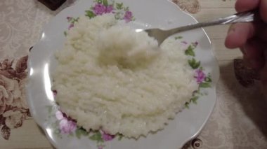 Tabakta pirinç lapası. Haşlanmış pirinç. Adam pilav yiyor. Yüksek kalite 4K görüntü. Hainanese tavuklu pilav ya da tavuklu pilav - Asya usulü. Kil tencerede pilav, Dolly shot