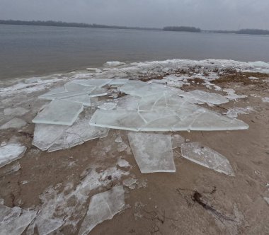 blocks of ice on the shore. big ice floes on the sand. Melting ice. Spring ice drift on the river. Ice close-up. thaw. Melted ice floes on the surface of blue water.