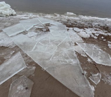 blocks of ice on the shore. big ice floes on the sand. Melting ice. Spring ice drift on the river. Ice close-up. thaw. Melted ice floes on the surface of blue water.