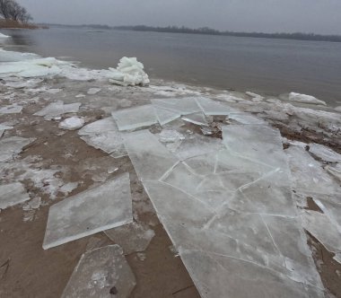 blocks of ice on the shore. big ice floes on the sand. Melting ice. Spring ice drift on the river. Ice close-up. thaw. Melted ice floes on the surface of blue water.