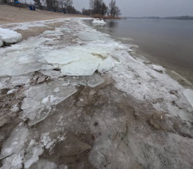 blocks of ice on the shore. big ice floes on the sand. Melting ice. Spring ice drift on the river. Ice close-up. thaw. Melted ice floes on the surface of blue water.