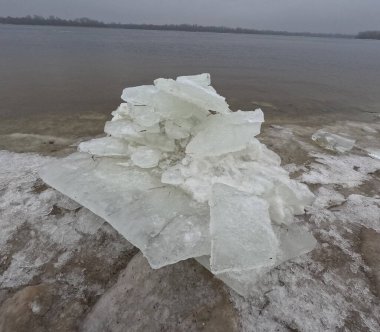 blocks of ice on the shore. big ice floes on the sand. Melting ice. Spring ice drift on the river. Ice close-up. thaw. Melted ice floes on the surface of blue water.