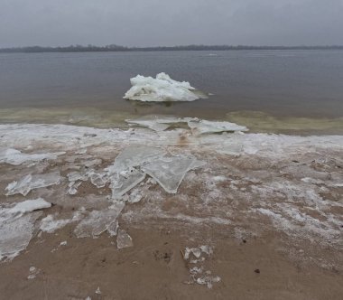 blocks of ice on the shore. big ice floes on the sand. Melting ice. Spring ice drift on the river. Ice close-up. thaw. Melted ice floes on the surface of blue water.