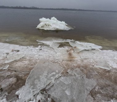 blocks of ice on the shore. big ice floes on the sand. Melting ice. Spring ice drift on the river. Ice close-up. thaw. Melted ice floes on the surface of blue water.