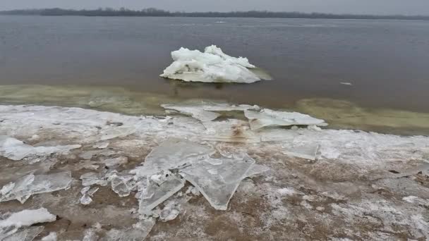 海岸上的冰块 大冰块漂浮在沙滩上 融化的冰 春天的冰在河上漂流 冰上特写解冻 融化的冰漂浮在蓝色的水面上 — 图库视频影像