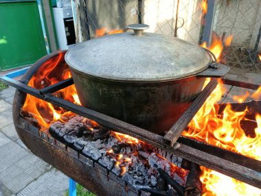 pot on fire. kettle on fire. Cooking on an Open Fire in a Tourist Pot. Cooking at the stake in a tourist bowler hat. Hiking. Tourist pot at bonfire. Large pot on a campfire on a camping trip