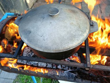 pot on fire. kettle on fire. Cooking on an Open Fire in a Tourist Pot. Cooking at the stake in a tourist bowler hat. Hiking. Tourist pot at bonfire. Large pot on a campfire on a camping trip