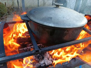 pot on fire. kettle on fire. Cooking on an Open Fire in a Tourist Pot. Cooking at the stake in a tourist bowler hat. Hiking. Tourist pot at bonfire. Large pot on a campfire on a camping trip
