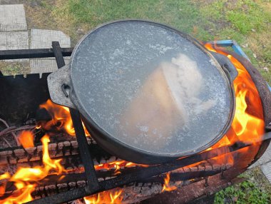 pot on fire. kettle on fire. Cooking on an Open Fire in a Tourist Pot. Cooking at the stake in a tourist bowler hat. Hiking. Tourist pot at bonfire. Large pot on a campfire on a camping trip