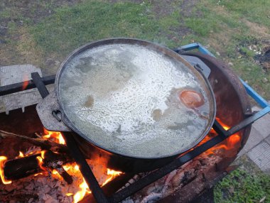 pot on fire. kettle on fire. Cooking on an Open Fire in a Tourist Pot. Cooking at the stake in a tourist bowler hat. Hiking. Tourist pot at bonfire. Large pot on a campfire on a camping trip