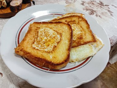 scrambled eggs in bread. An egg and sausage pieces fried in the middle of a slice of toast, also known as an egg in a basket. Close-up of a meal made from eggs in bread. Homemade breakfast idea.