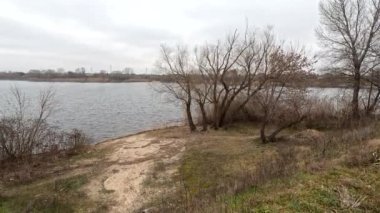 cloudy landscape on the banks of the river. natural landscape with water. walk by the water. Narrow path over a cliff. Water break. Strong wind near the river. Winter beach. Without people. Ukrainian nature. Ukraine.