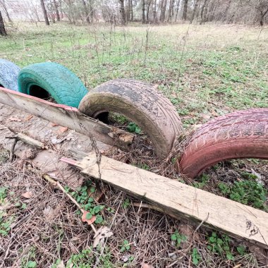 old tires. wheels are dug into the ground. painted tires. Old Retro Kid's Playground With Rubber Tires In The Park. Wall Of The Old Tires On The Racing Track. Pile of waste tires.