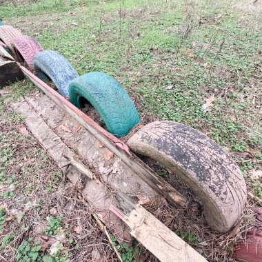old tires. wheels are dug into the ground. painted tires. Old Retro Kid's Playground With Rubber Tires In The Park. Wall Of The Old Tires On The Racing Track. Pile of waste tires.