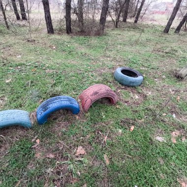 old tires. wheels are dug into the ground. painted tires. Old Retro Kid's Playground With Rubber Tires In The Park. Wall Of The Old Tires On The Racing Track. Pile of waste tires.