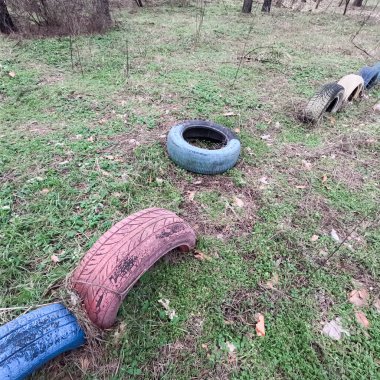 old tires. wheels are dug into the ground. painted tires. Old Retro Kid's Playground With Rubber Tires In The Park. Wall Of The Old Tires On The Racing Track. Pile of waste tires.