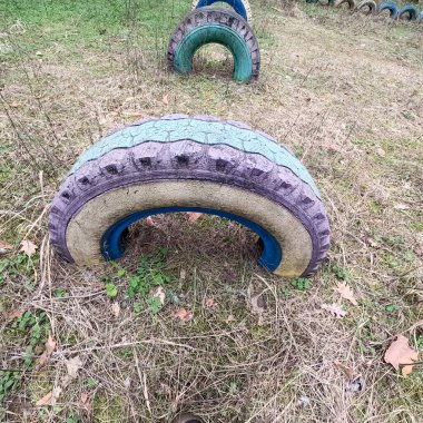 old tires. wheels are dug into the ground. painted tires. Old Retro Kid's Playground With Rubber Tires In The Park. Wall Of The Old Tires On The Racing Track. Pile of waste tires.