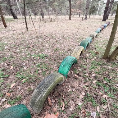 old tires. wheels are dug into the ground. painted tires. Old Retro Kid's Playground With Rubber Tires In The Park. Wall Of The Old Tires On The Racing Track. Pile of waste tires.