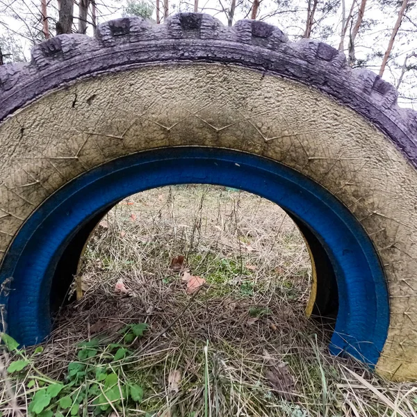 old tires. wheels are dug into the ground. painted tires. Old Retro Kid\'s Playground With Rubber Tires In The Park. Wall Of The Old Tires On The Racing Track. Pile of waste tires.