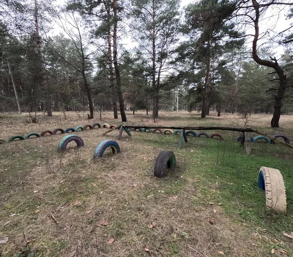 abandoned playground. Children's playground in the forest. Old Retro Kid's Playground With Rubber Tires In The Park. Surreal playground,abandoned swings in rural countryside. Ukraine.