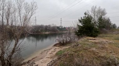 cloudy landscape on the banks of the river. high cliff above the water. Wind shakes dry reeds and makes ripples on a river with a reflection of a clouds. natural landscape with water. Dnepr River. Ukraine.