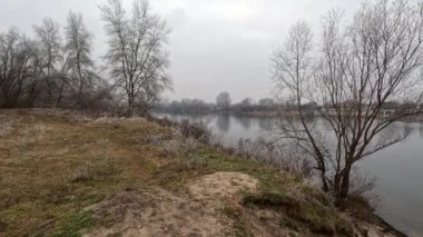 cloudy landscape on the banks of the river. high cliff above the water. Wind shakes dry reeds and makes ripples on a river with a reflection of a clouds. natural landscape with water. Dnepr River. Ukraine.
