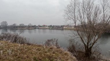 cloudy landscape on the banks of the river. high cliff above the water. Wind shakes dry reeds and makes ripples on a river with a reflection of a clouds. natural landscape with water. Dnepr River. Ukraine.