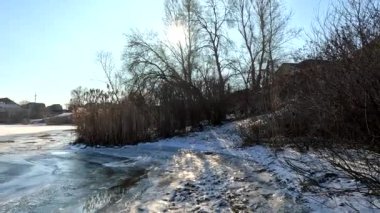 winter sunny landscape on the river bank. Beautiful scenic landscape view of a calm river flowing on a bright sunny clear blue sky. Dnieper river in winter. Ukrainian winter landscape. River bank and ice.