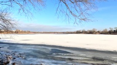 winter sunny landscape on the river bank. Beautiful scenic landscape view of a calm river flowing on a bright sunny clear blue sky. Dnieper river in winter. Ukrainian winter landscape. River bank and ice.
