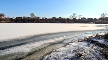 winter sunny landscape on the river bank. Beautiful scenic landscape view of a calm river flowing on a bright sunny clear blue sky. Dnieper river in winter. Ukrainian winter landscape. River bank and ice.