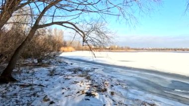 winter sunny landscape on the river bank. Beautiful scenic landscape view of a calm river flowing on a bright sunny clear blue sky. Dnieper river in winter. Ukrainian winter landscape. River bank and ice.