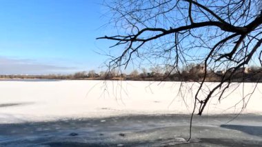 winter sunny landscape on the river bank. Beautiful scenic landscape view of a calm river flowing on a bright sunny clear blue sky. Dnieper river in winter. Ukrainian winter landscape. River bank and ice.