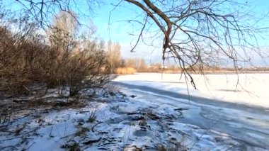 winter sunny landscape on the river bank. Beautiful scenic landscape view of a calm river flowing on a bright sunny clear blue sky. Dnieper river in winter. Ukrainian winter landscape. River bank and ice.