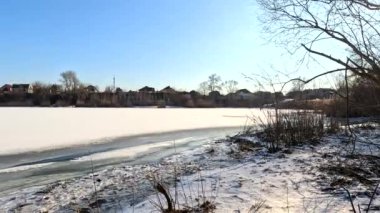 winter sunny landscape on the river bank. Beautiful scenic landscape view of a calm river flowing on a bright sunny clear blue sky. Dnieper river in winter. Ukrainian winter landscape. River bank and ice.